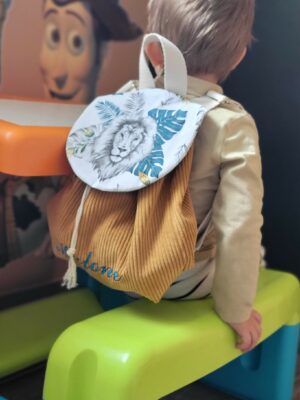 Sac à dos pour bébé en velours moutarde et motif lion, personnalisable avec un prénom brodé. Parfait pour accompagner les tout-petits lors de leurs premières sorties, chez la nounou, à la crèche ou à l'école maternelle